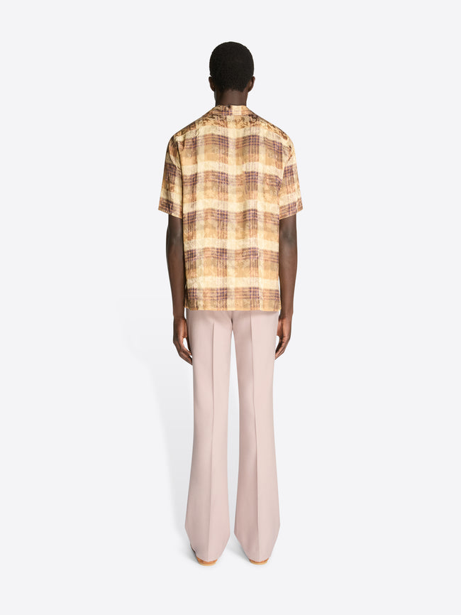 Backside of a model wearing a tan check print boxy shirt and light pink pants on a white background