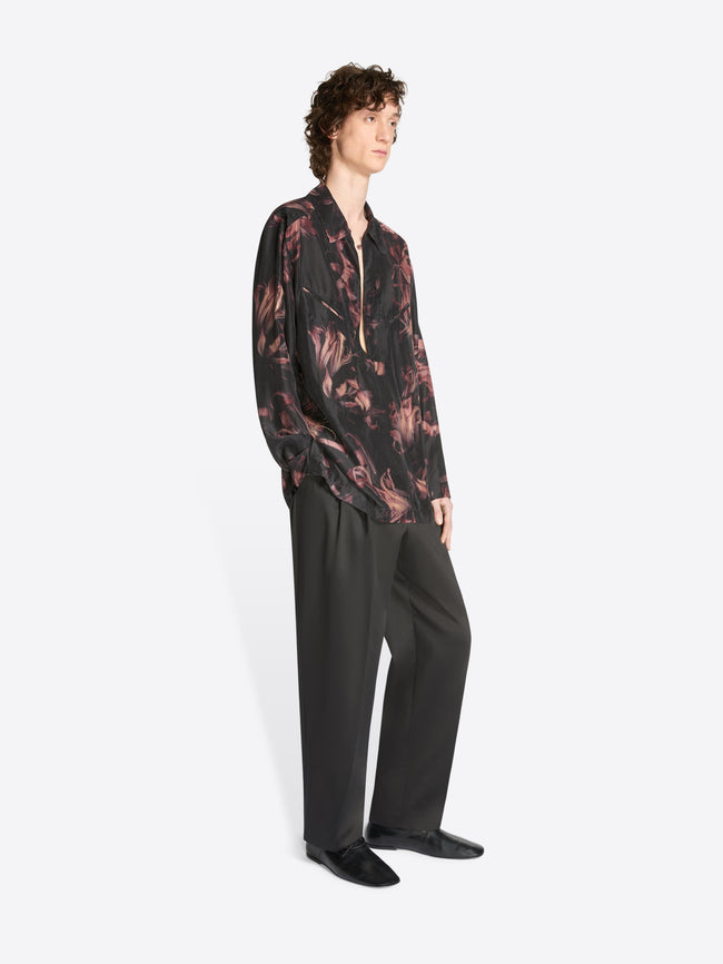 Model wearing a black and old rose colored popover silk shirt and black pants on a white background