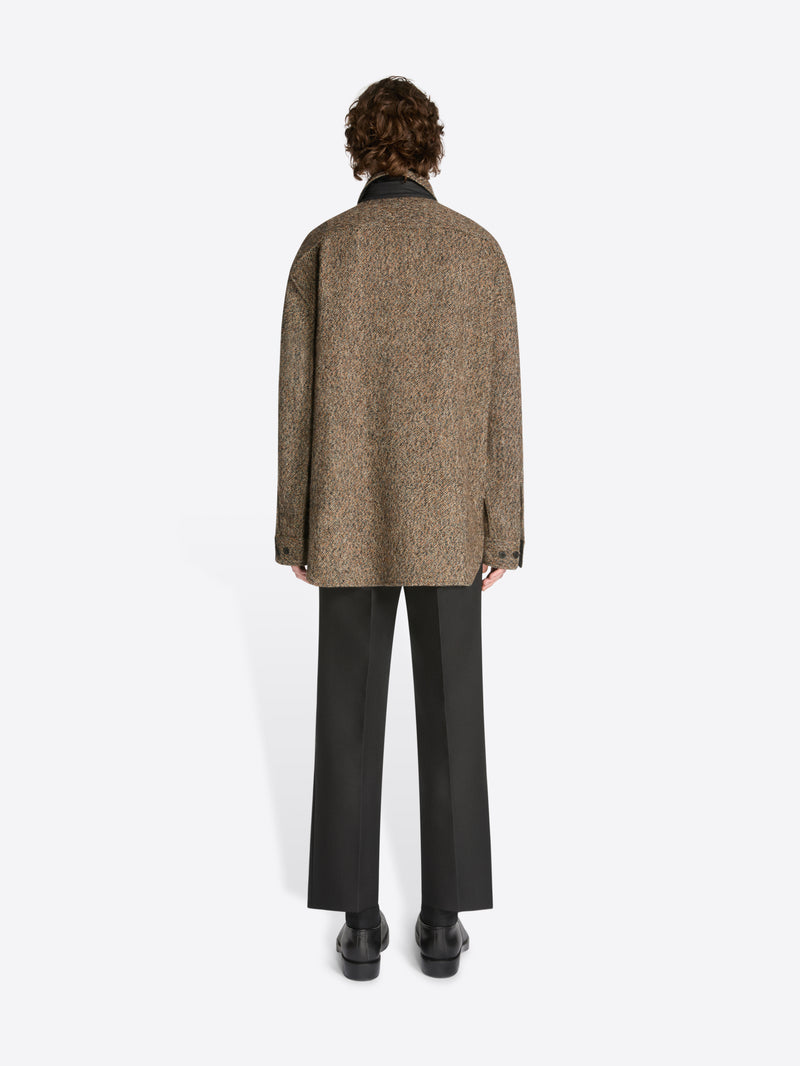 Person wearing a brown textured coat on a white background