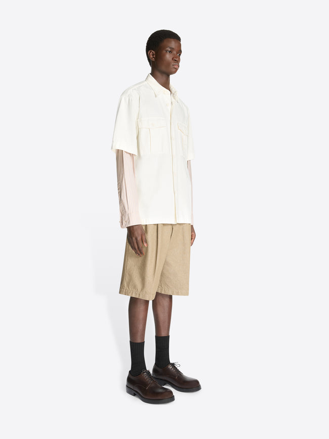 Model wearing an off white colored contrast sleeves denim shirt and beige shorts on a white background