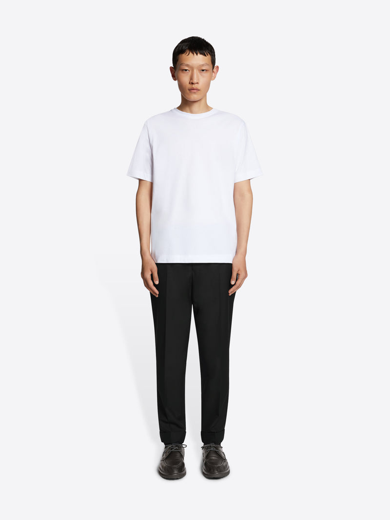 Person wearing a white t-shirt and black pants on a white background