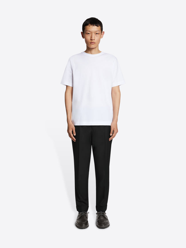 Person wearing a white t-shirt and black pants on a white background