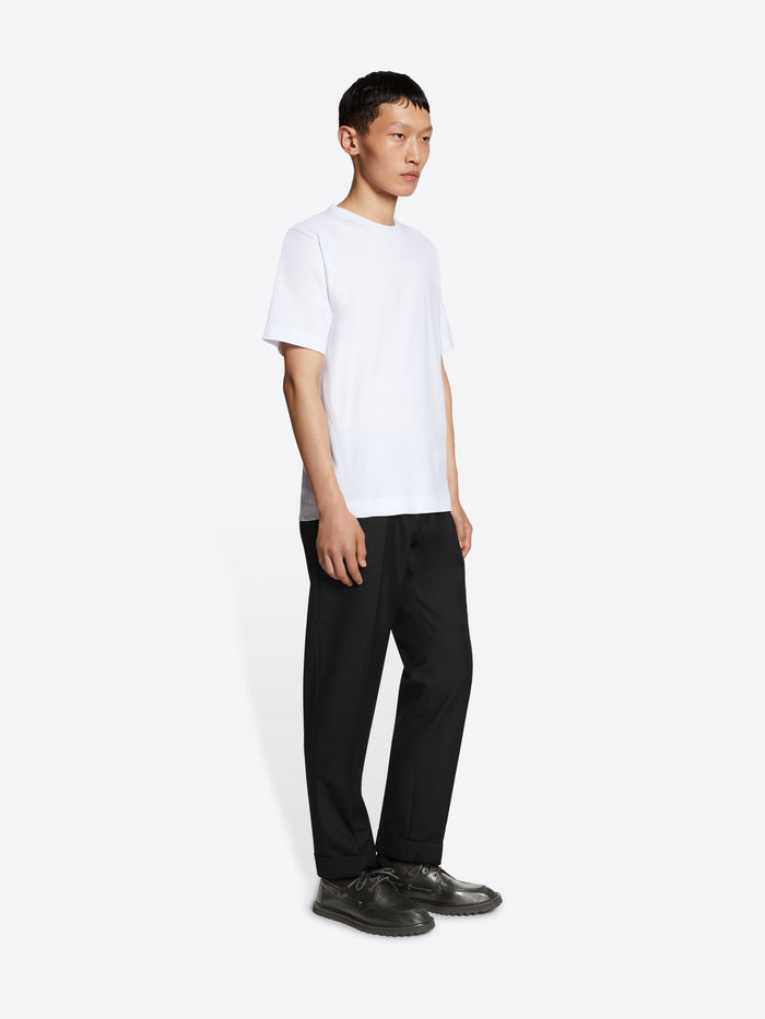 Person wearing a white t-shirt and black pants on a white background