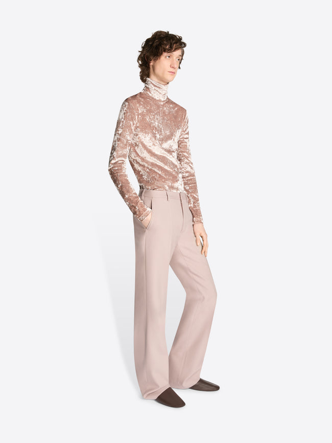 Person wearing a sheer top and beige pants on a white background