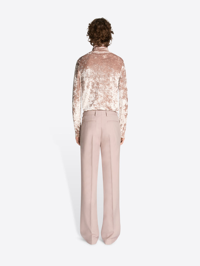 Person wearing a sequin blouse and beige pants on a white background