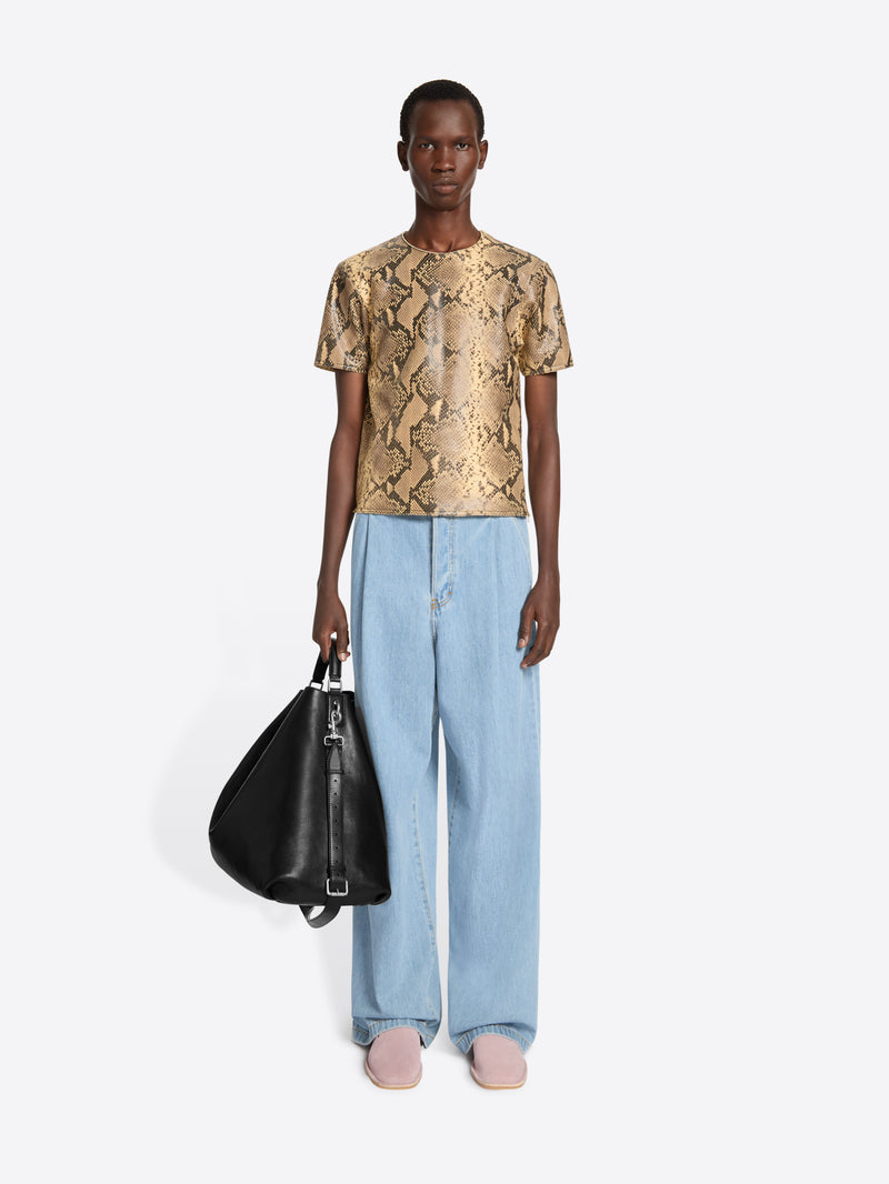 Person wearing a patterned top and light blue pants on a white background