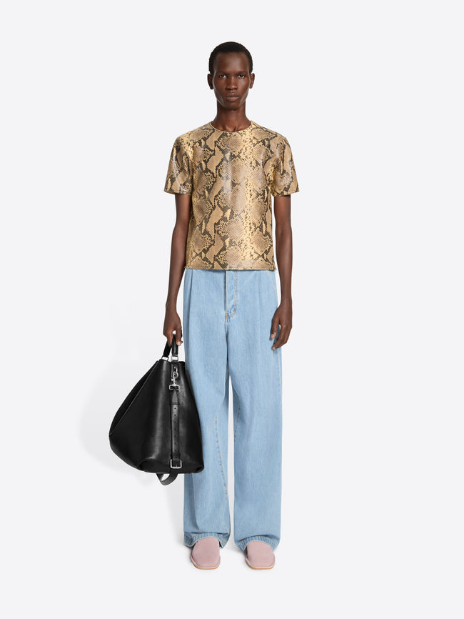 Person wearing a patterned top and light blue pants on a white background