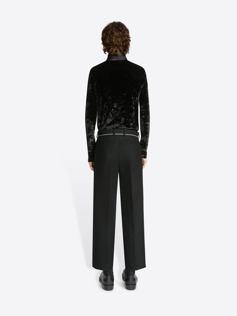 Person wearing a black velvet top and pants on a white background