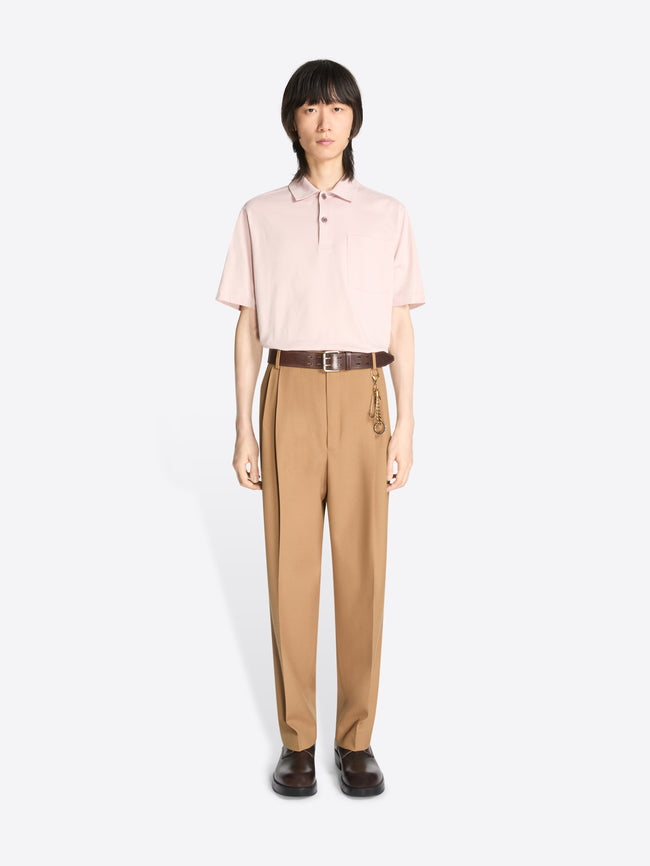 Model wearing a light pink colored shirt and a pair of a colored pleated wool pants on a white background