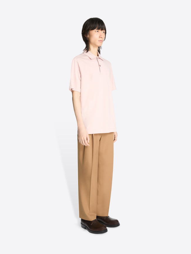 Model wearing a pale pink cotton polo shirt and beige pants on a white background