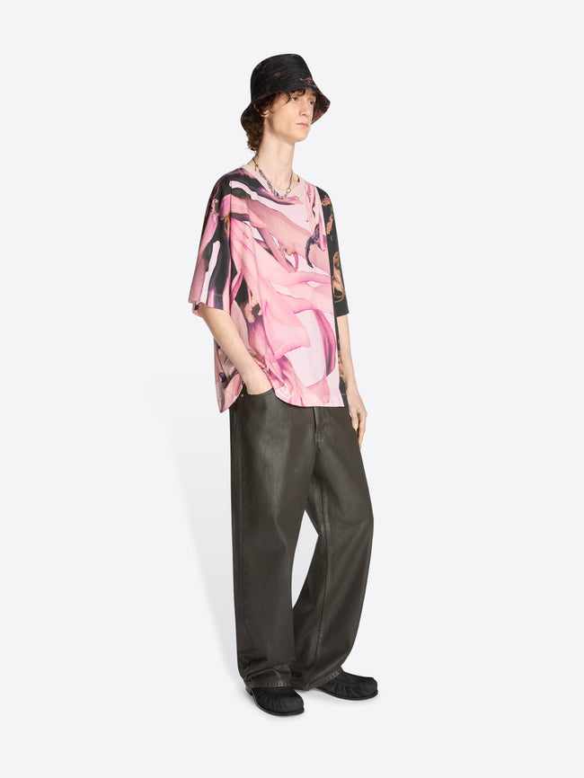 Model wearing floral pale pink oversized tee with black accent and black coated pants on a white background