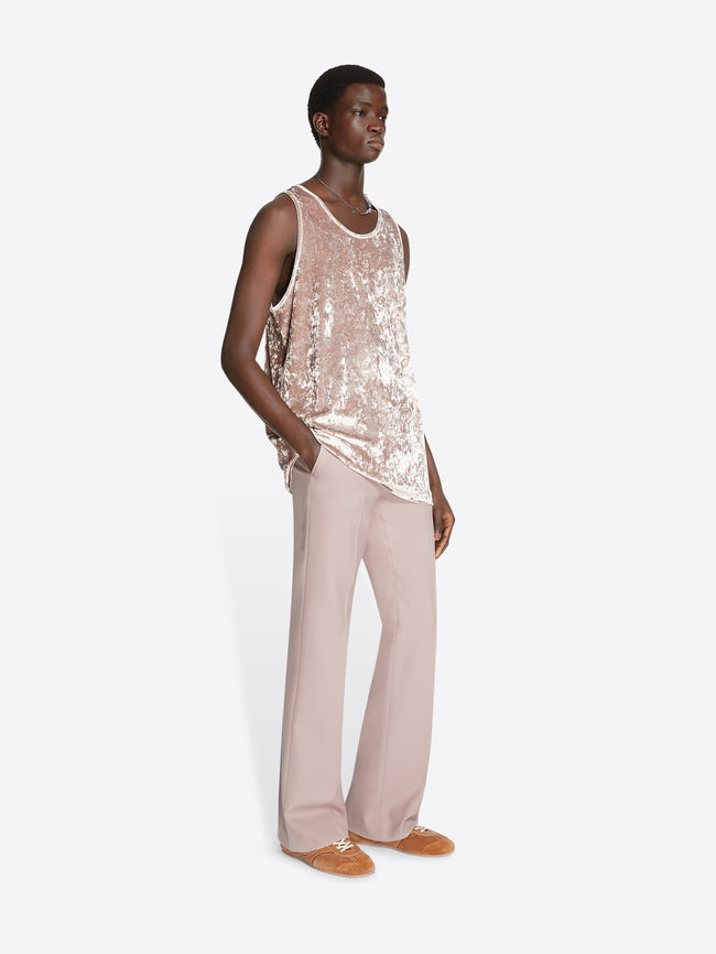 Model wearing an old rose colored velvet tank top and light rose pants on a white background