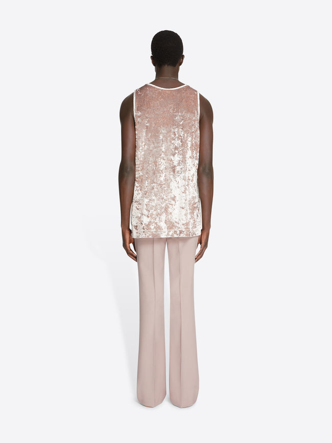 Model wearing an old rose colored velvet tank top and light rose pants on a white background