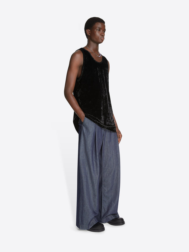 Model wearing a black velvet tank top and denim pants on a white background