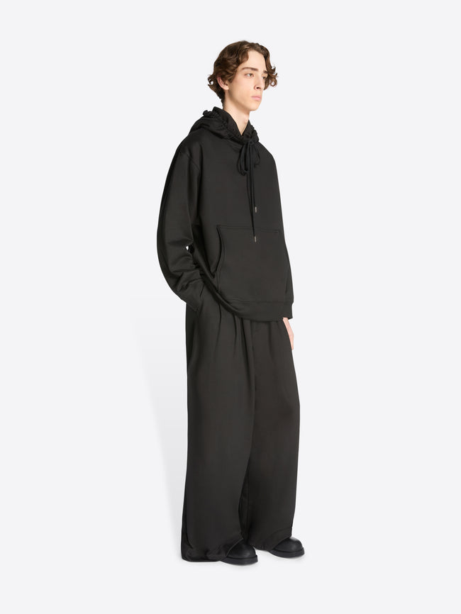Model wearing a black loose fit hoodie and matching sweatpants on a white background