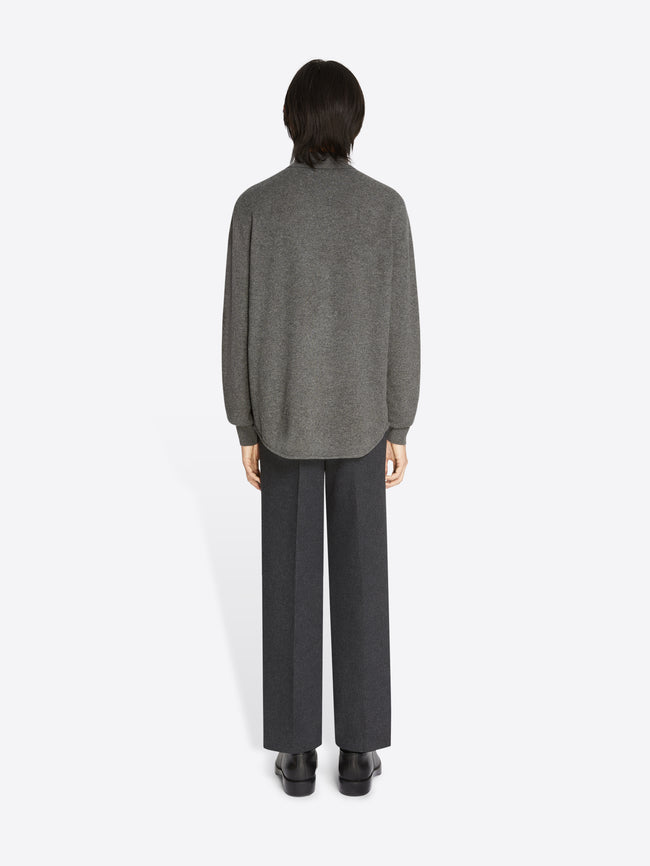 Backside of a model wearing a dark grey pair of pants and a dark grey cashmere polo shirt on a white background