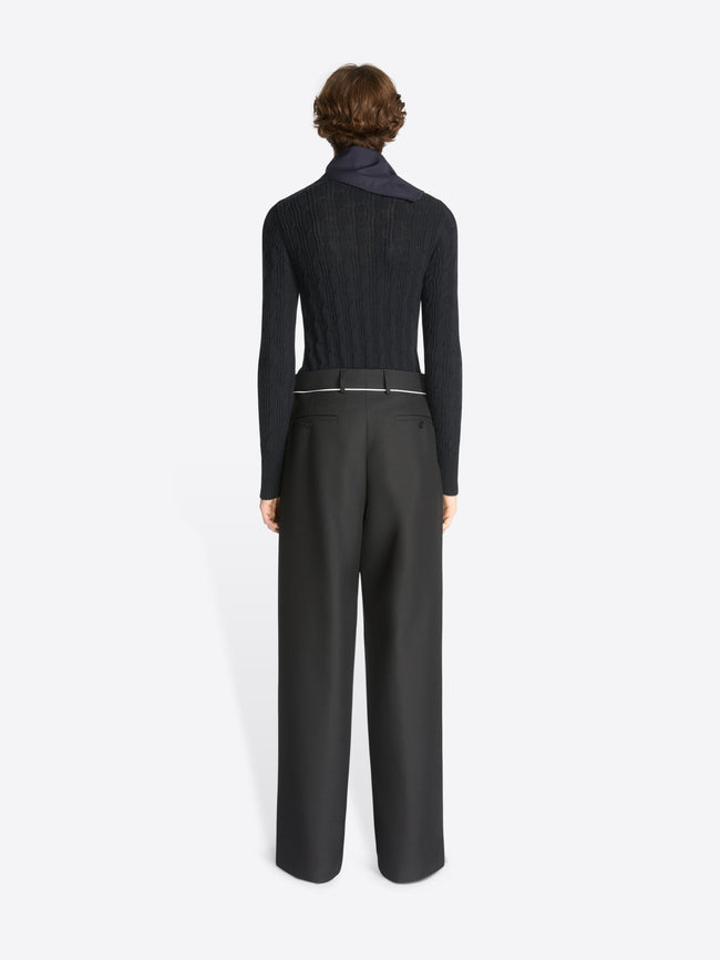Backside of a model wearing a black wool sweater and black pants on a white background