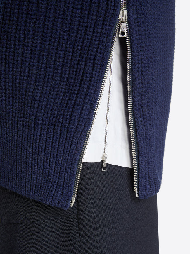 Close up of a model wearing a navy zipped wool sweater on a white background