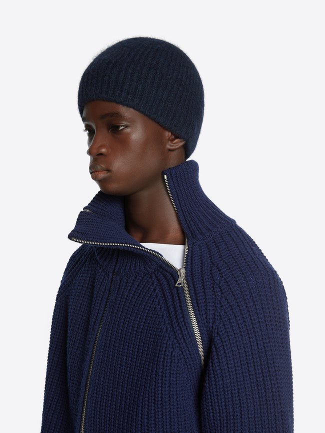 Close up of a model wearing a navy zipped wool sweater on a white background