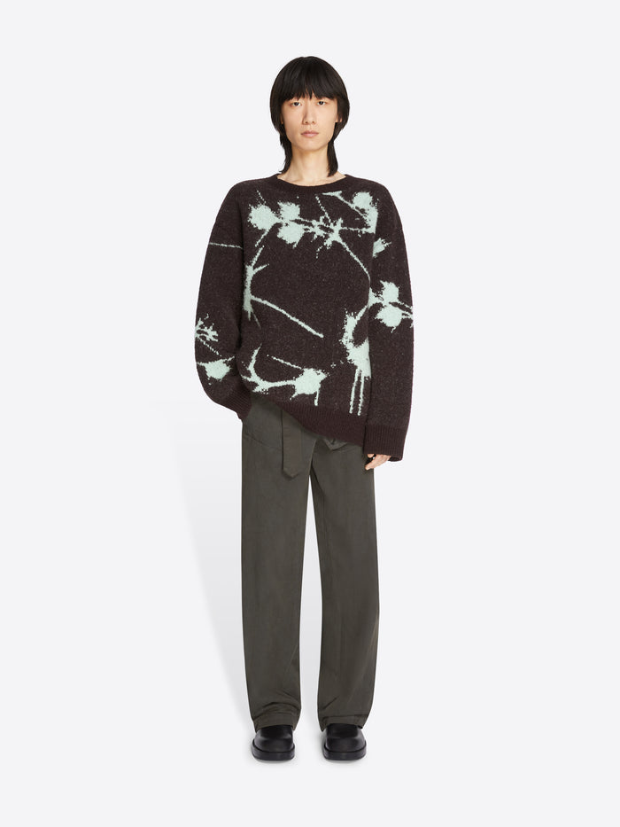 Person wearing a black and white tie-dye sweater with gray pants on a white background