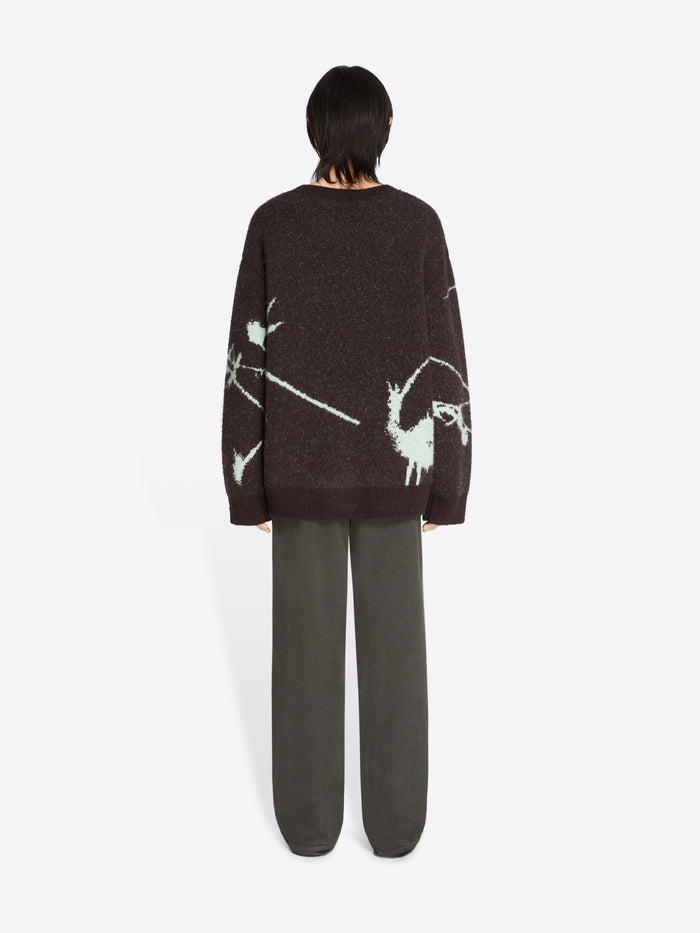 Person wearing a dark sweater with abstract designs on a white background