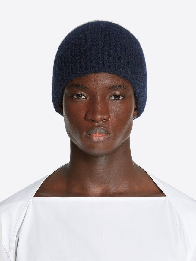 Model wearing a navy colored wool beanie on a white background