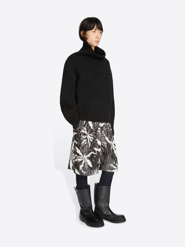 Model wearing a pair of black and white patterned shorts and a black oversized wool sweater on a white background