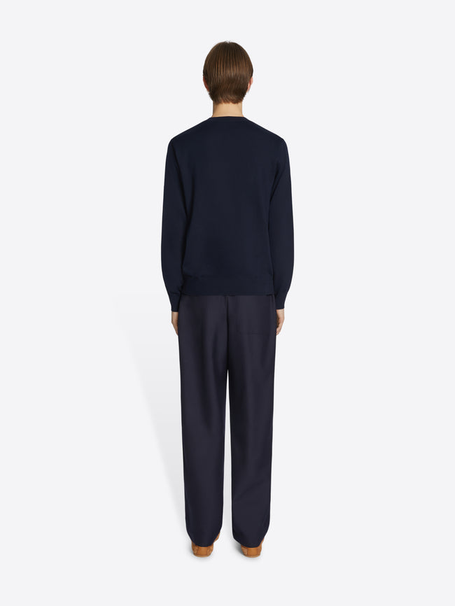 Person wearing a navy blue sweater and pants on a white background