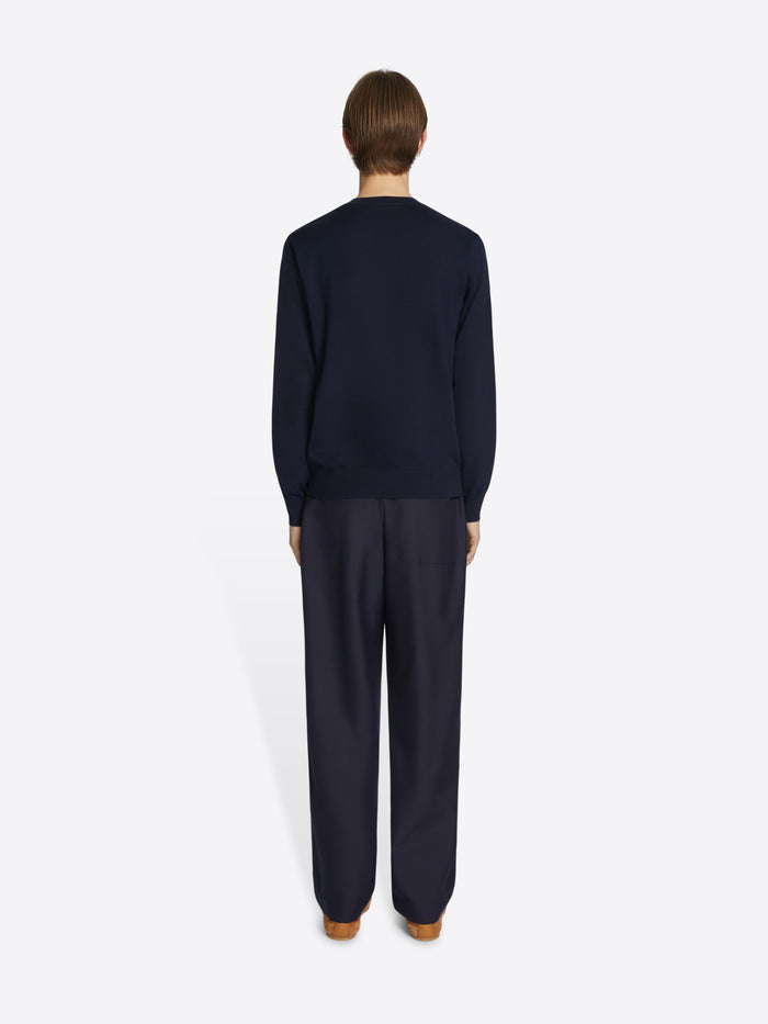 Person wearing a navy blue sweater and pants on a white background