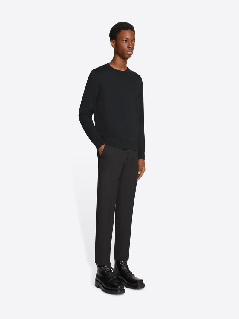 Man wearing a black sweater, pants, and shoes on a white background