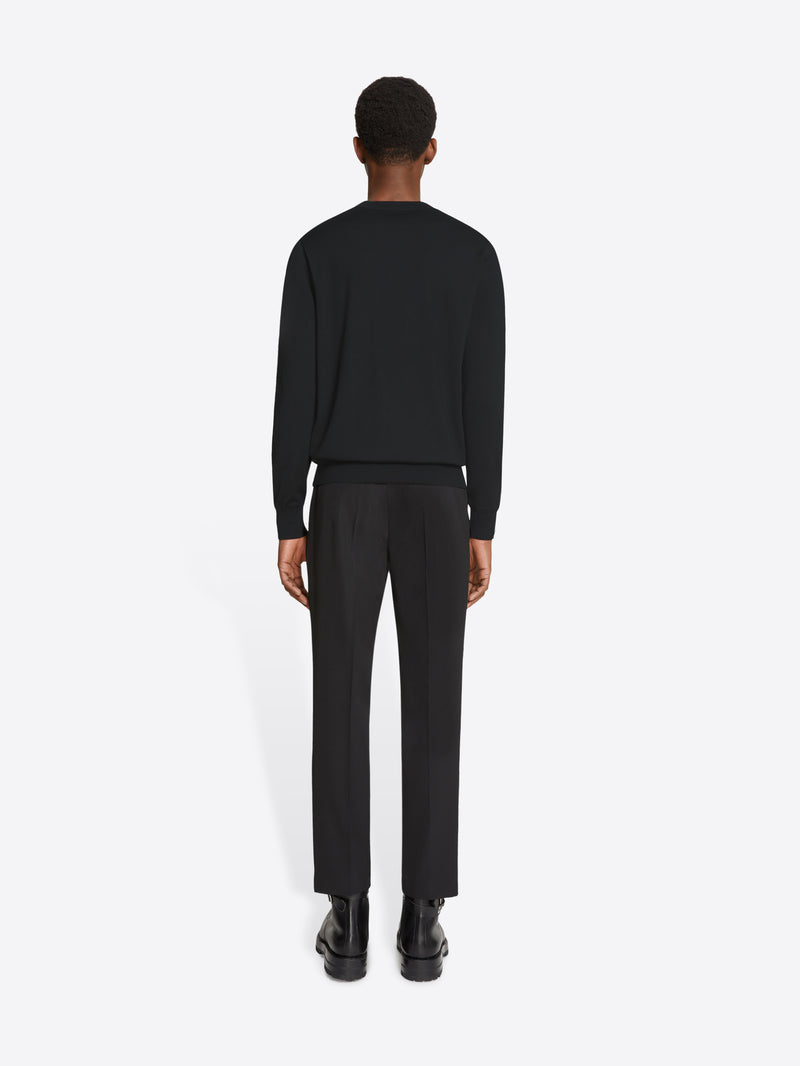 Person wearing a black sweater and pants on a white background