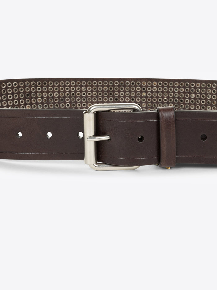 Close up of a brown belt with a silver buckle and metallic detailing on a white background