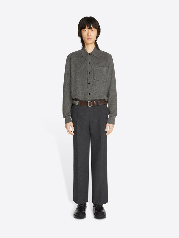 Person wearing a brown belt with a silver buckle and metallic detailing on a white background