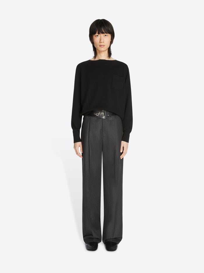 Person wearing a black sweater, belt and pants on a white background