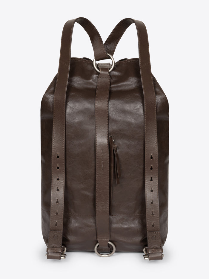 Backside of a brown, adjustable leather bag with a front clasp on a white background