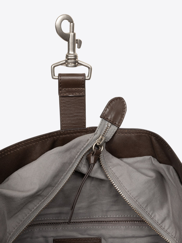 Close-up of a brown and grey leather bag with a zipper and metal clasp on a white background