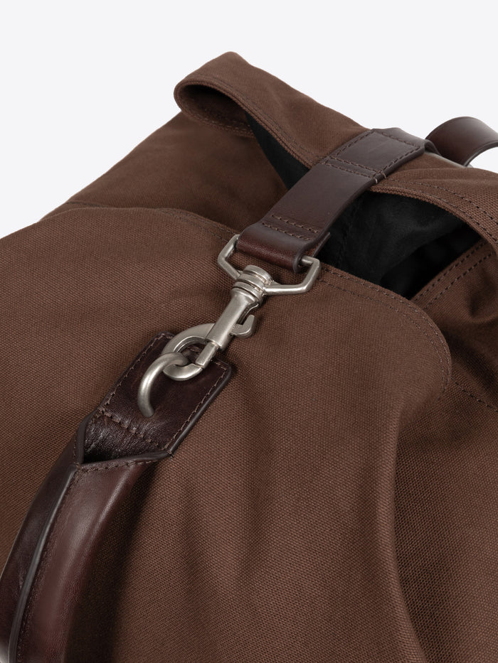 Close up of a metallic clasp on a brown duffel bag on a white background