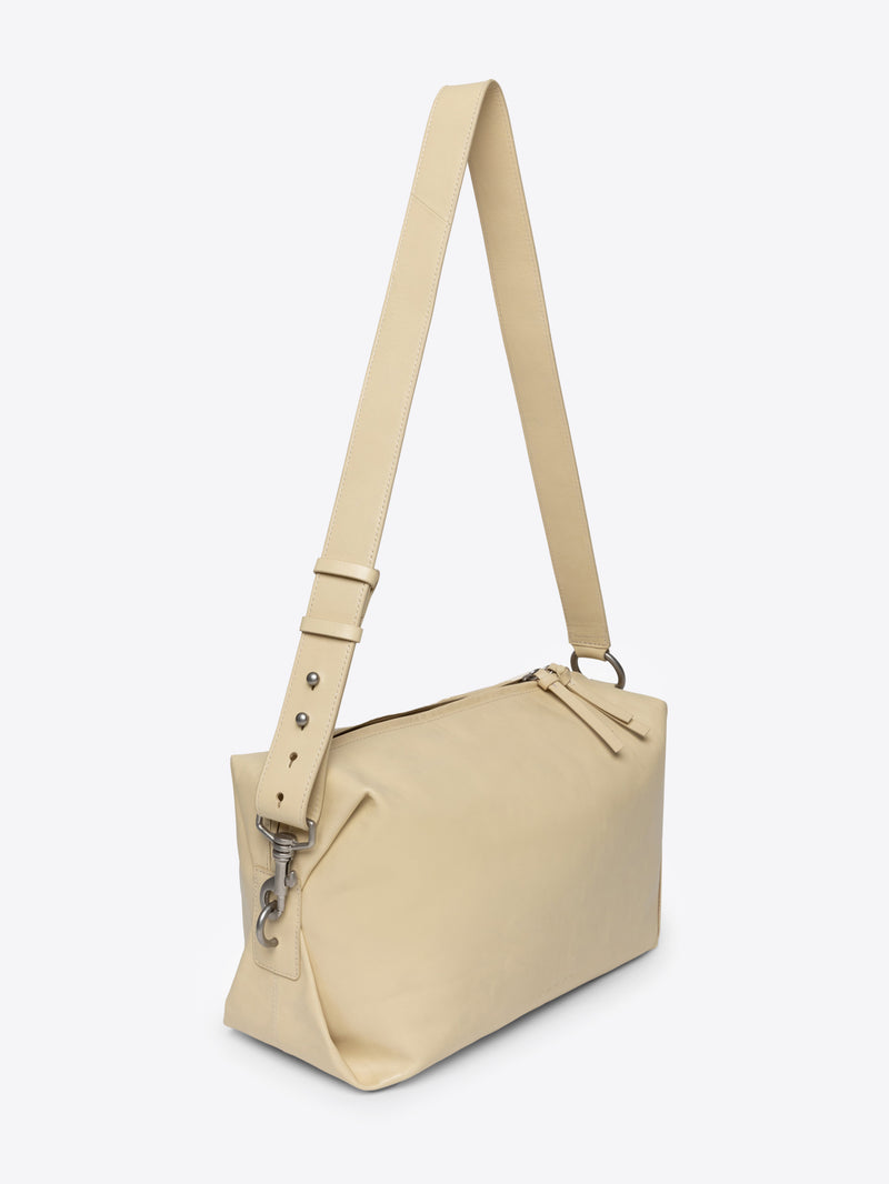 Sand colored handbag with a strap on a white background