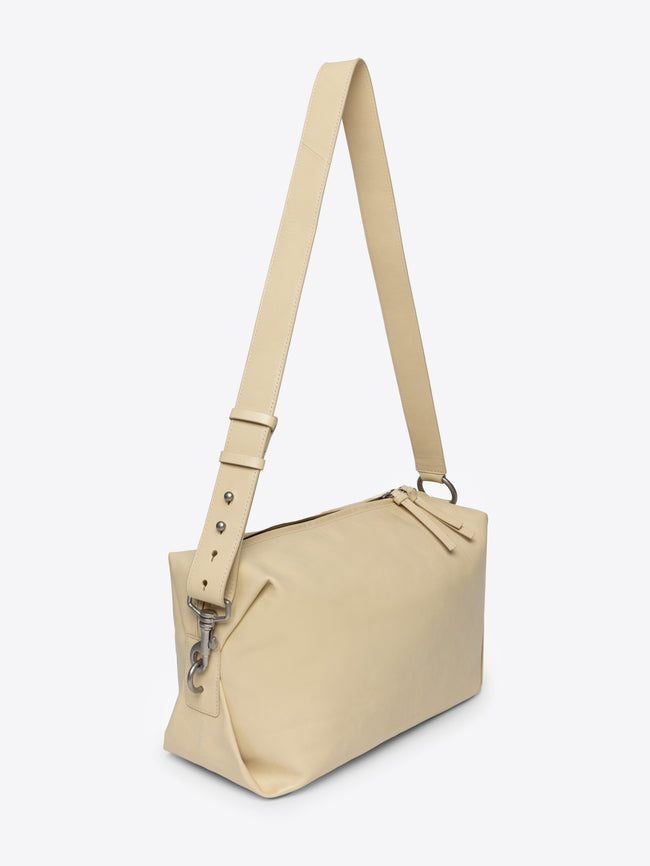 Sand colored handbag with a strap on a white background