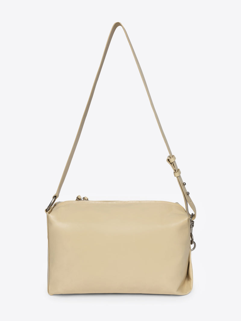 Sand colored handbag with a strap on a white background