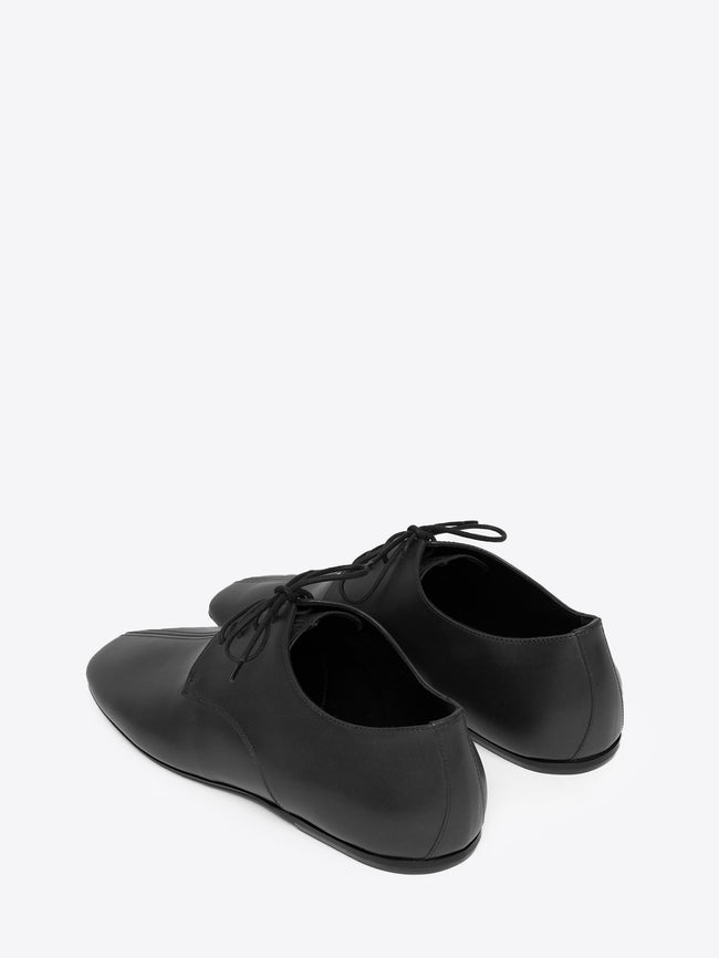Backside of a pair of black leather oxford shoes on a white background