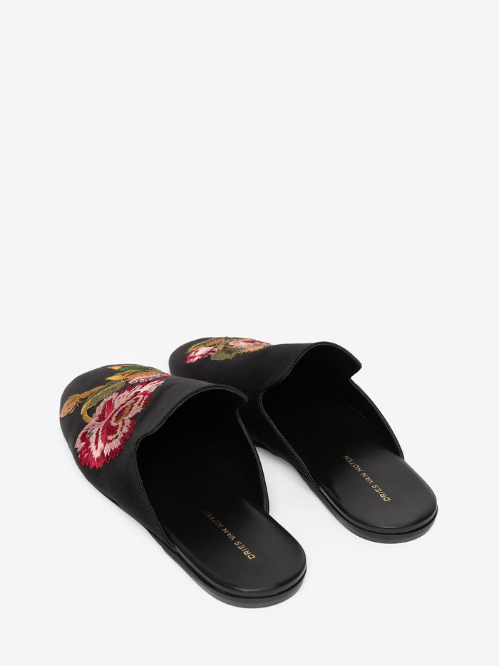 Backside of black slippers with floral embroidery on a white background