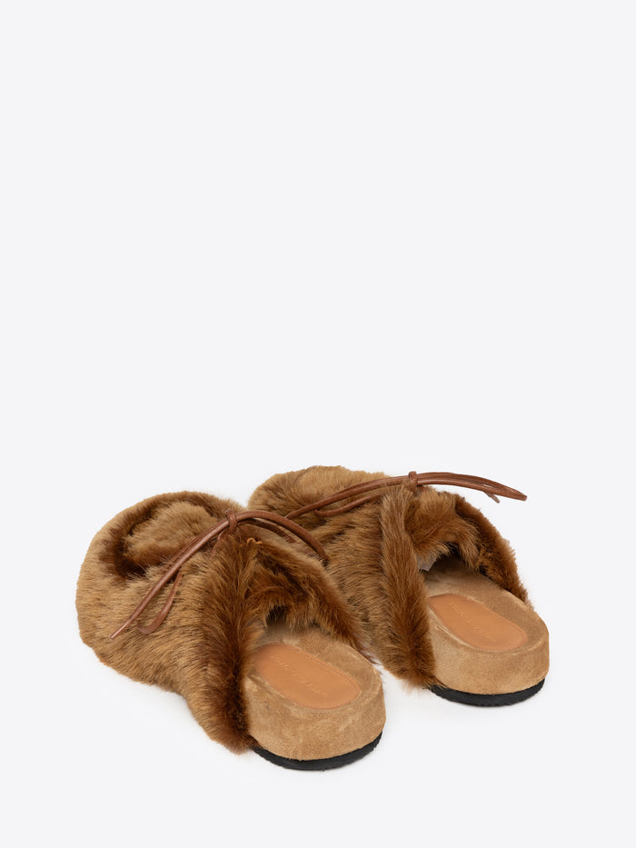 A pair of tan fluffy slippers on a white background