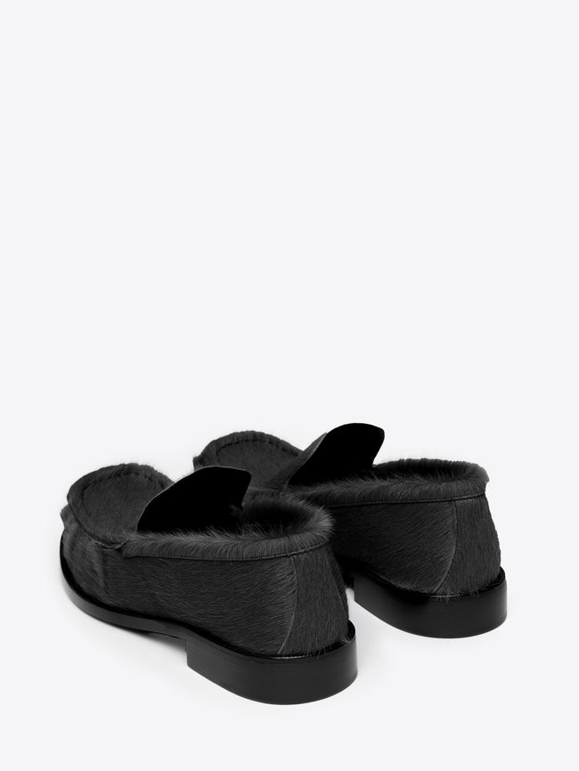 Backside of a pair of black leather loafer shoes on a white background