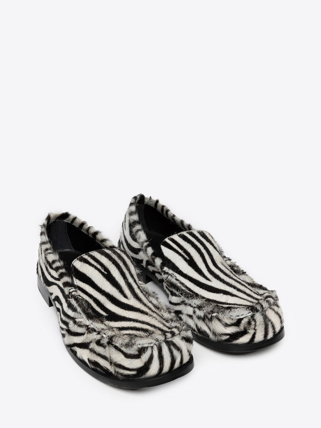 Pair of zebra print leather loafers on a white background