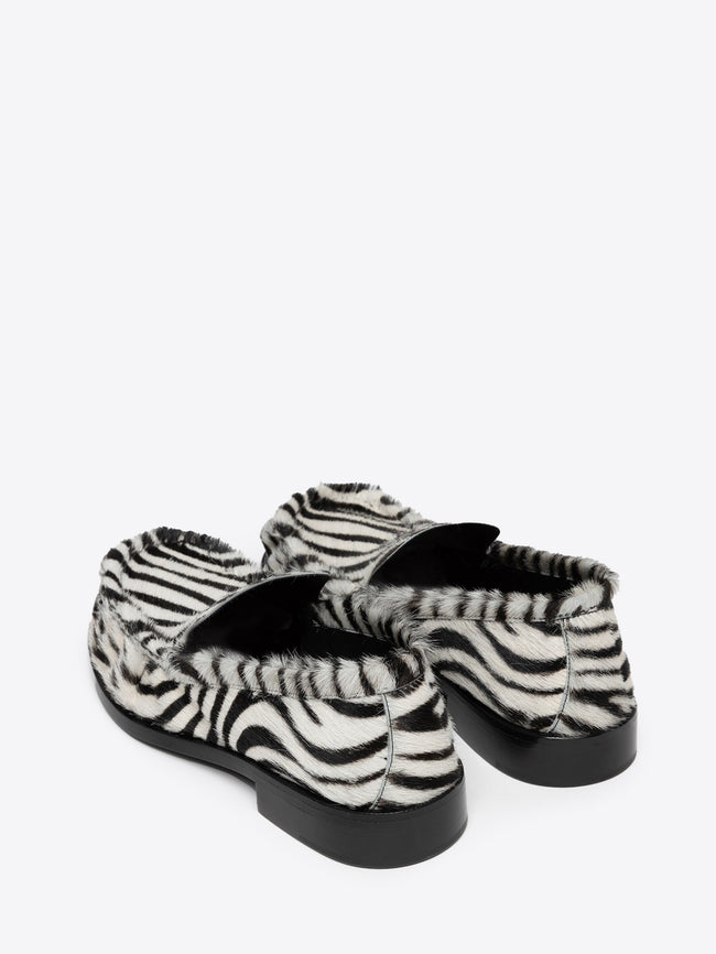 Pair of zebra print leather loafers on a white background