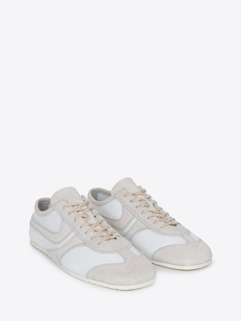 Pair of white suede sneakers with beige accents on a white background