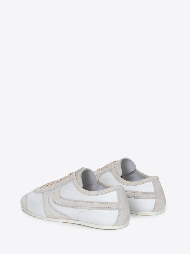 Backside of a pair of white suede sneakers with beige accents on a white background