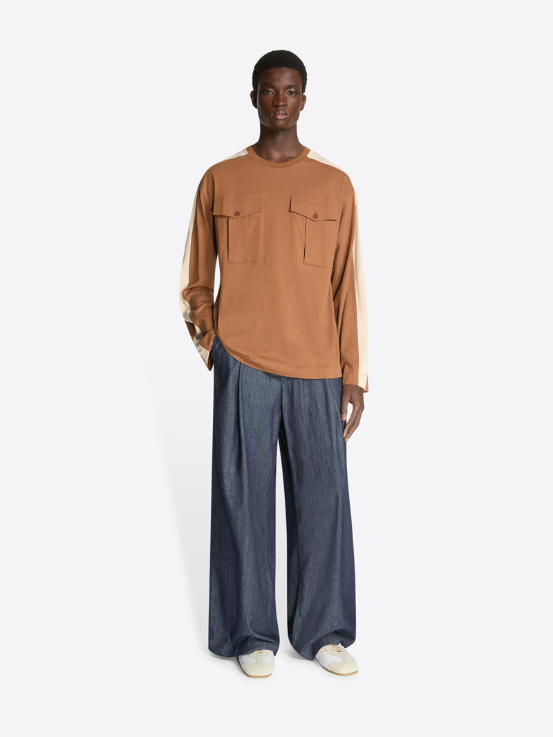 Person wearing a brown long-sleeve shirt and blue pants on a white background