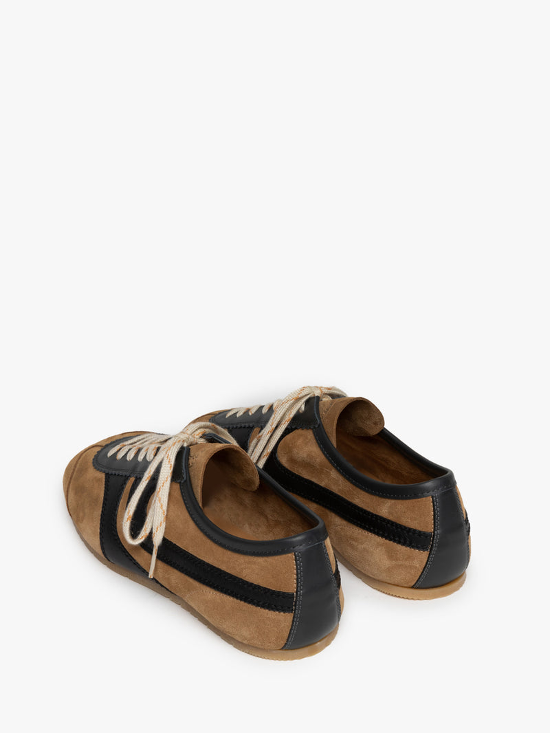 Backside of a pair of brown with black accents suede sneakers on a white background
